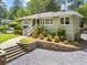 Brick home with manicured landscaping, stone retaining wall, gravel driveway, and inviting walkway at 2180 Howell Mill Nw Rd, Atlanta, GA 30318