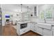 Charming kitchen with island, white cabinets, stainless steel appliances, and hardwood floors that lead to a dining area at 2180 Howell Mill Nw Rd, Atlanta, GA 30318