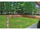 Backyard featuring a flat grassy area, a retaining wall, and mature trees at 2445 Kings Point Dr, Dunwoody, GA 30338