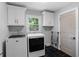 Well-lit laundry room with white cabinets, black floors, and modern washer and dryer at 2445 Kings Point Dr, Dunwoody, GA 30338