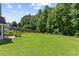 Spacious backyard with green grass, mature trees, and a pergola-covered patio at 3234 Baymount Way, Lawrenceville, GA 30043