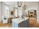 Open concept kitchen and dining area boasts island with marble countertop, wood floors, and stylish lighting at 11277 Serenbe Ln, Chattahoochee Hills, GA 30268