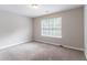 Comfortable bedroom features a large window and neutral-toned walls and carpet at 3732 Landgraf Cv, Decatur, GA 30034