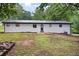 Backyard view featuring a white brick home with a metal roof and a fire pit area at 4651 Palm Dr, Douglasville, GA 30135