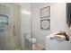 Tiled shower with a frameless glass enclosure, toilet, and white vanity with art on the wall at 1398 Woodland Ave, Atlanta, GA 30316