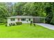 Charming single-story home with a lush green lawn, pink door, and carport, nestled among mature trees at 2343 Dawn Dr, Decatur, GA 30032