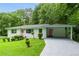 Charming single-story home with a lush green lawn, pink door, and carport, nestled among mature trees at 2343 Dawn Dr, Decatur, GA 30032