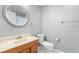Well-lit bathroom featuring a round mirror, wood vanity, and neutral gray walls at 2717 Hearthstone Cir, Marietta, GA 30062