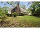 Large backyard with mature trees and lush grass, showcasing the home's brick accents and architectural details at 1595 Bakers Glen Dr, Atlanta, GA 30350