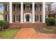 Close-up of the stately brick home featuring white columns, a black front door, and brick stairs at 1595 Bakers Glen Dr, Atlanta, GA 30350