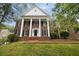 Stately brick home featuring white columns, black shutters, and a manicured front lawn on a lush, green lot at 1595 Bakers Glen Dr, Atlanta, GA 30350