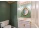 Traditional powder room featuring floral wallpaper, green accent wall, and vanity with oval mirror at 1595 Bakers Glen Dr, Atlanta, GA 30350