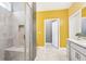 Bathroom featuring a tiled walk-in shower, double vanity, and vibrant yellow accent wall at 160 Amherst Way, Fayetteville, GA 30215