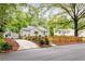 Inviting home nestled among mature trees, showcasing a charming picket fence and lush landscaping along the concrete driveway at 1583 Braeburn Se Dr, Atlanta, GA 30316