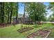 Spacious backyard featuring raised garden beds, a manicured lawn, and a peaceful setting at 5301 Regency Lake Ct, Sugar Hill, GA 30518