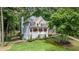 Charming brick and siding home featuring a covered porch, well-manicured lawn, and mature trees at 5301 Regency Lake Ct, Sugar Hill, GA 30518