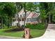 Attractive brick home with a covered front porch, surrounded by lush greenery and mature trees at 5301 Regency Lake Ct, Sugar Hill, GA 30518