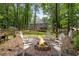 Inviting fire pit area with comfortable seating and a serene backdrop of mature trees and landscaping at 5301 Regency Lake Ct, Sugar Hill, GA 30518