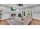 Cozy living room features a brick fireplace, hardwood floors, ceiling fan, and an outdoor patio view at 5301 Regency Lake Ct, Sugar Hill, GA 30518