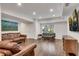 Bright living room with hardwood floors, modern sofas, and a large window with backyard views at 5301 Regency Lake Ct, Sugar Hill, GA 30518