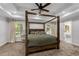 Spacious main bedroom featuring a four-poster bed, tray ceiling, and backyard views at 5301 Regency Lake Ct, Sugar Hill, GA 30518