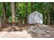 Backyard shed and sitting area with a rustic accent piece, surrounded by mature trees and natural beauty at 5301 Regency Lake Ct, Sugar Hill, GA 30518