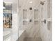 Close-up of the marble-tiled shower with geometric insets, a bench, and dual showerheads at 6170 Wellington Ct, Cumming, GA 30040