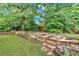 Landscaped backyard featuring a stone retaining wall and lush greenery, creating a serene and private outdoor space at 123 Patrick Way, Marietta, GA 30064