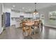 Open dining area with a wooden table and seating, flowing into the kitchen with white cabinets and stainless steel appliances at 7190 Tributary Ct, Cumming, GA 30040