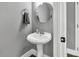 Elegant bathroom with a pedestal sink, modern faucet, and stylish round mirror at 577 Cypher Drive, Suwanee, GA 30024