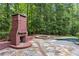 Backyard area with a stone fireplace and a stone-lined hot tub with a swimming pool in the distance at 63 Lewellen Dr, Marietta, GA 30064