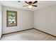 Neutral bedroom with light carpet, one window overlooking trees, ceiling fan, and light colored walls at 9800 Woodfall Dr, Roswell, GA 30076