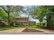 Beautiful two-story brick home with mature trees, a circular driveway, and manicured landscaping at 9800 Woodfall Dr, Roswell, GA 30076