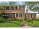 Charming two-story brick home with black shutters and a beautifully landscaped front yard at 9800 Woodfall Dr, Roswell, GA 30076