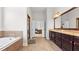 Bright bathroom with soaking tub, tiled floors, double sink vanity, and access to the main bedroom at 1980 Marcia Overlook Dr, Cumming, GA 30041