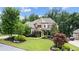 Charming brick home featuring manicured lawn, stone accents, and mature trees on a sunny day at 1980 Marcia Overlook Dr, Cumming, GA 30041