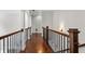 Elegant upstairs hallway showcasing hardwood floors, wood and wrought iron railing, and decorative lighting at 1980 Marcia Overlook Dr, Cumming, GA 30041
