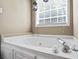 A close-up view of a soaking tub with chrome hardware and a white tiled surround, illuminated by natural light at 380 Russell Rd, Lawrenceville, GA 30043