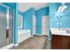 Bright blue bathroom with tub/shower, tile flooring, and double doors to hallway at 7027 Walham Grv, Duluth, GA 30097