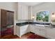 Kitchen with white cabinets, black countertops, farmhouse sink, a large window and an adjacent mudroom area at 27 Sessions Nw St, Marietta, GA 30060