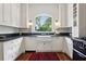 Bright kitchen features white cabinets, black countertops, farmhouse sink, and a large window offering a scenic view at 27 Sessions Nw St, Marietta, GA 30060