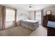 Neutral bedroom featuring carpet, metal bed frame, ceiling fan and bright windows with decorative drapes at 3589 Stone Ridge Trl, Douglasville, GA 30134