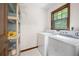 Laundry area with white washer and dryer, built-in storage and small window at 3589 Stone Ridge Trl, Douglasville, GA 30134