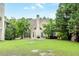 Large backyard with a lush lawn, mature trees, and the rear exterior of the home with a chimney at 1921 Northbrooke Ln, Dunwoody, GA 30338