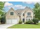 Inviting home featuring manicured lawn, neutral stucco, arched windows, and a two-car garage at 1921 Northbrooke Ln, Dunwoody, GA 30338
