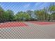 View of the community tennis court surrounded by trees, viewed through a chain link fence at 3385 Amhurst Pkwy, Atlanta, GA 30349
