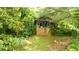 Exterior of a quaint, single-story home with a brick foundation nestled among mature trees and lush foliage at 12728 Bells Ferry Rd, Canton, GA 30114