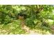 Exterior of a quaint, single-story home with a brick foundation nestled among mature trees and lush foliage at 12728 Bells Ferry Rd, Canton, GA 30114