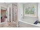 Bright bathroom featuring a soaking tub, glass enclosed shower, and marble floors at 520 Edgemore Rd, Canton, GA 30114