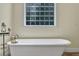 Bright bathroom featuring a soaking tub below a glass block window and vintage-style fixtures and wrought iron candle stand at 7212 Avalon Dr, Douglasville, GA 30135